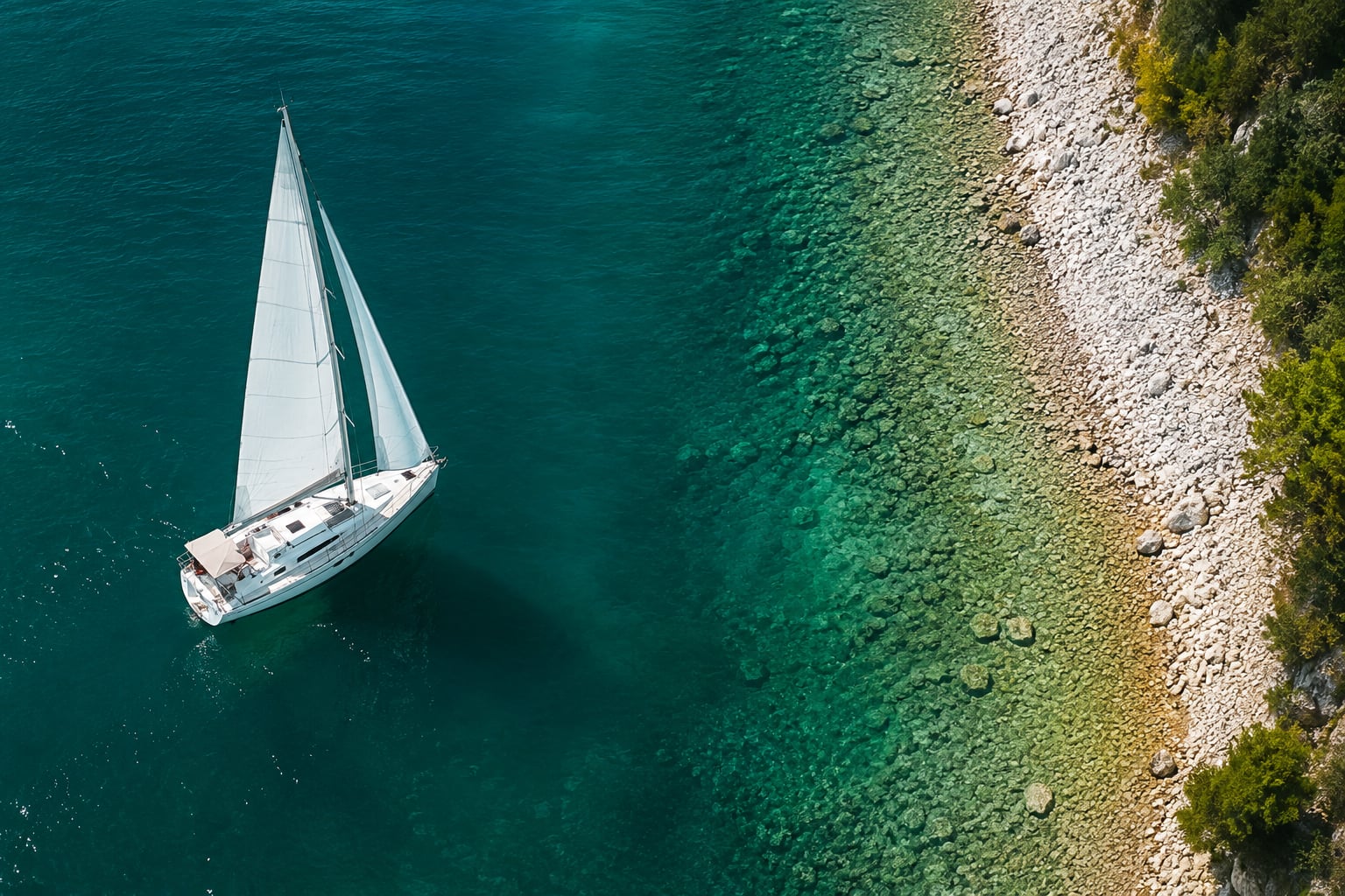 Veliero sulle acque cristalline del Lago di Garda tra le rive boscose